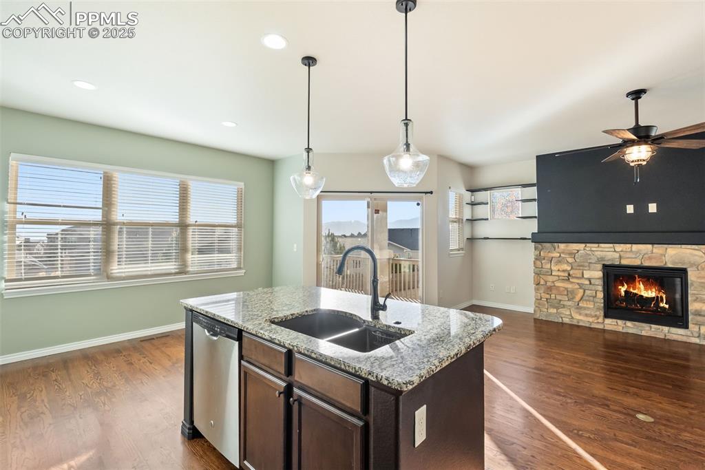 Image 14 of 43: Kitchen featuring light stone counters, dark brown cabinetry, dark wood-typ