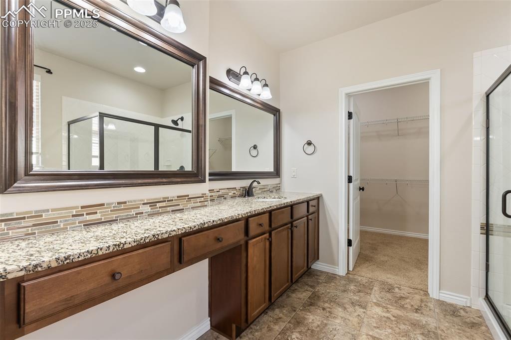 Image 24 of 43: Bathroom featuring vanity, a walk in closet, and a shower stall