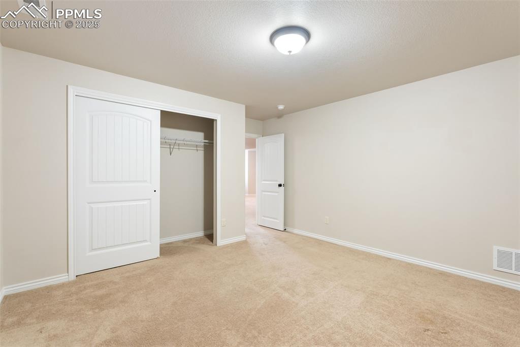 Image 35 of 43: Unfurnished bedroom featuring light colored carpet, a closet, and a texture