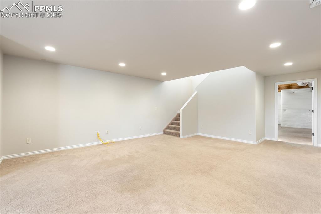 Image 36 of 43: Below grade area featuring stairway, light colored carpet, and recessed lig