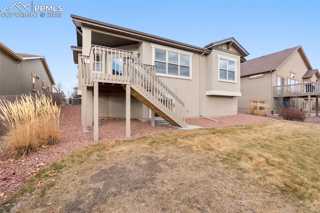 Image 43 of 43: Rear view of property featuring stucco siding, stairs, and a lawn