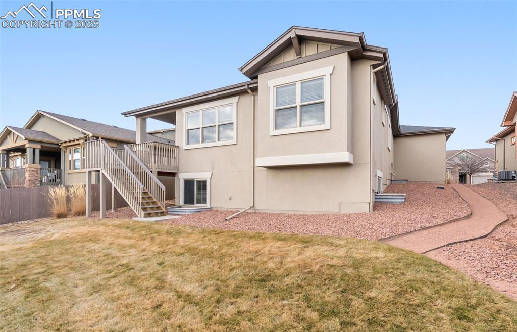Image 48 of 50: Rear view of house featuring stairs, stucco siding, and a wooden deck