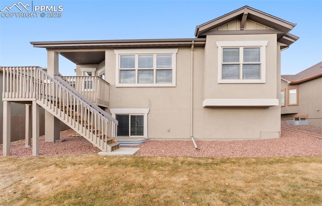 Image 49 of 50: Rear view of property featuring stucco siding, a lawn, and stairs