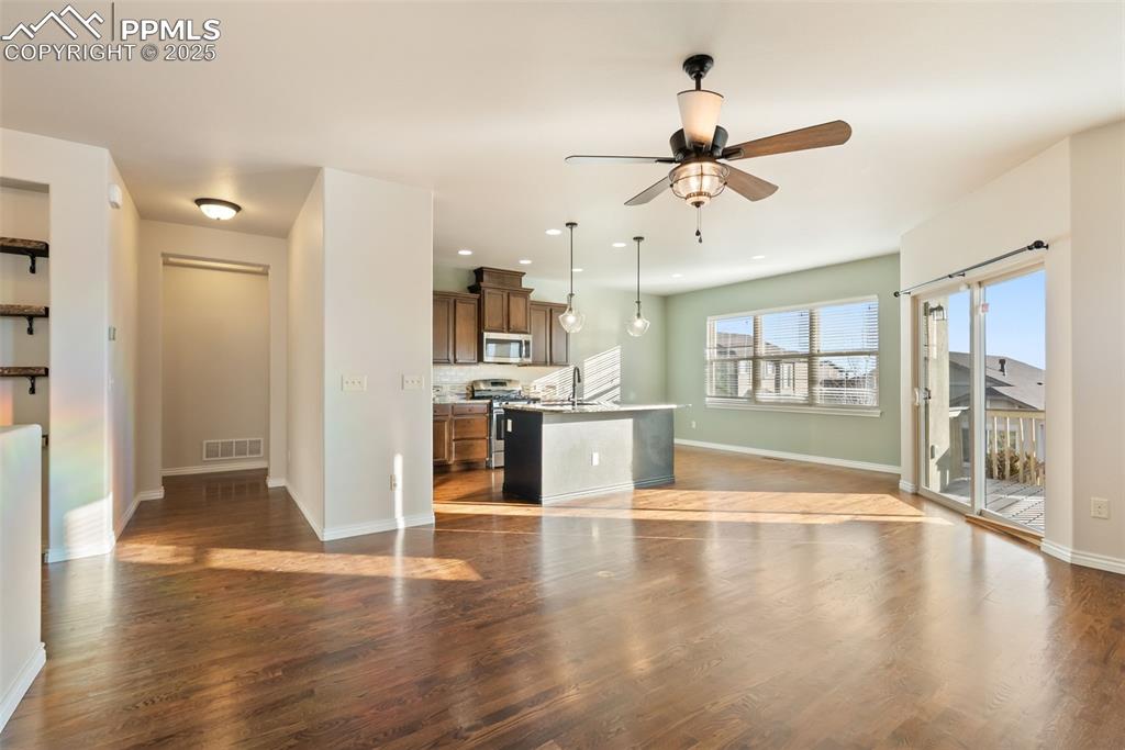 Image 8 of 43: Unfurnished living room featuring dark wood-type flooring, ceiling fan, and