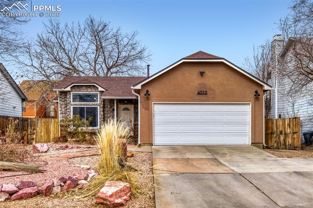 Image 2 of 27: Ranch-style home featuring stone siding, driveway, an attached garage, and