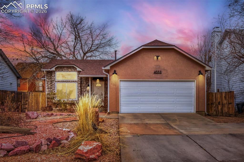 Image 27 of 27: Ranch-style home featuring stone siding, concrete driveway, a garage, and s
