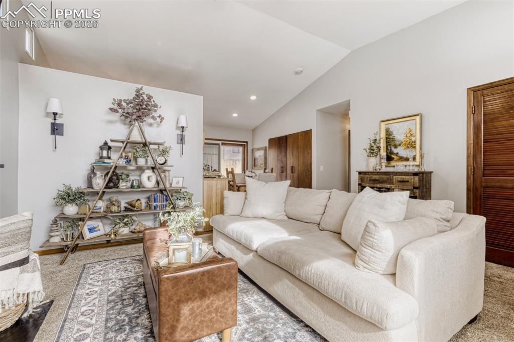 Image 4 of 27: Carpeted living room featuring lofted ceiling