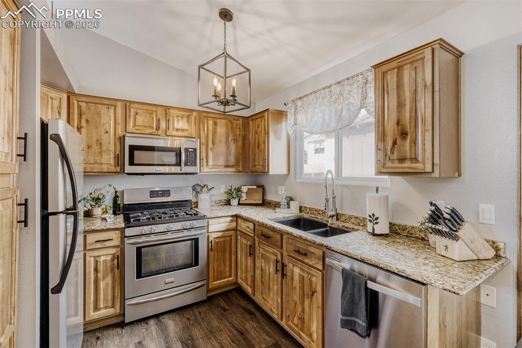 Image 7 of 27: Kitchen with stainless steel appliances, light stone counters, vaulted ceil