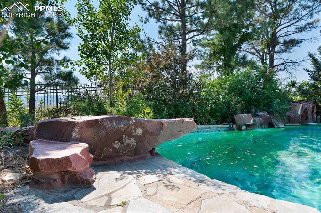 Image 40 of 50: This Resort Style Pool Has A "Flintstone" Diving Board Made Of Stone