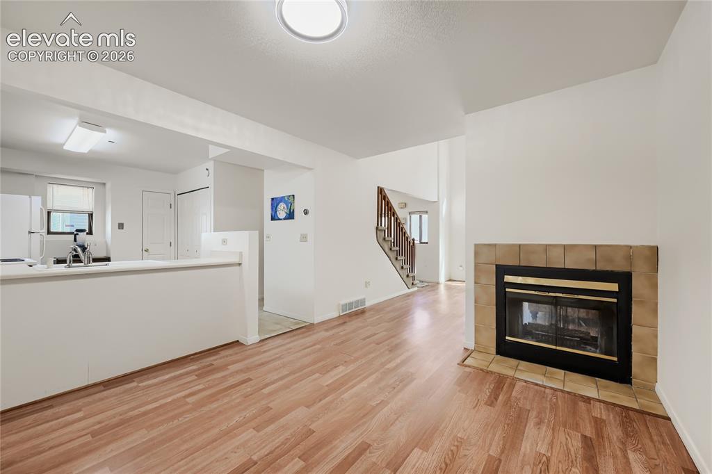 Image 10 of 37: Wood-finish flooring throughout, featuring a tiled fireplace with hearth, a