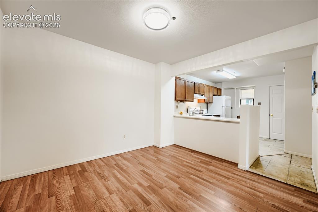 Image 11 of 37: Spacious living area with warm wood-finish flooring, recessed ceiling light