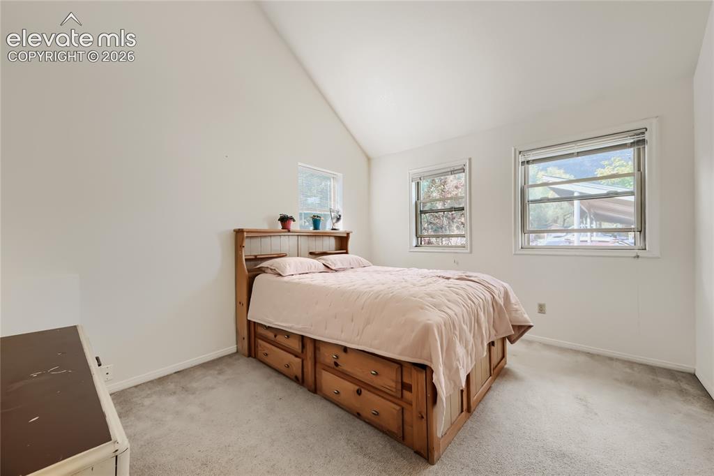 Image 17 of 37: Bright secondary bedroom featuring vaulted ceilings, multiple windows with 