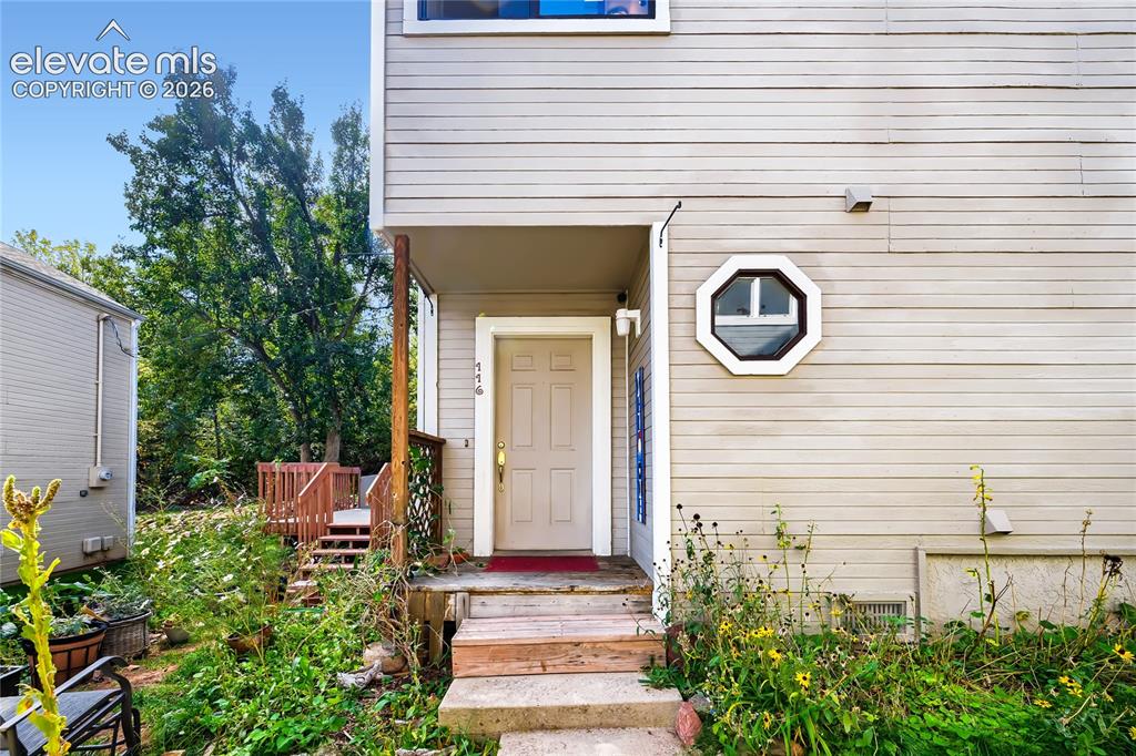 Image 2 of 37: Welcoming entry featuring a covered front porch with wooden steps, cream-co