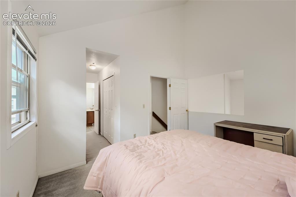 Image 20 of 37: Vaulted ceiling, white walls, carpet flooring, a window with horizontal bli