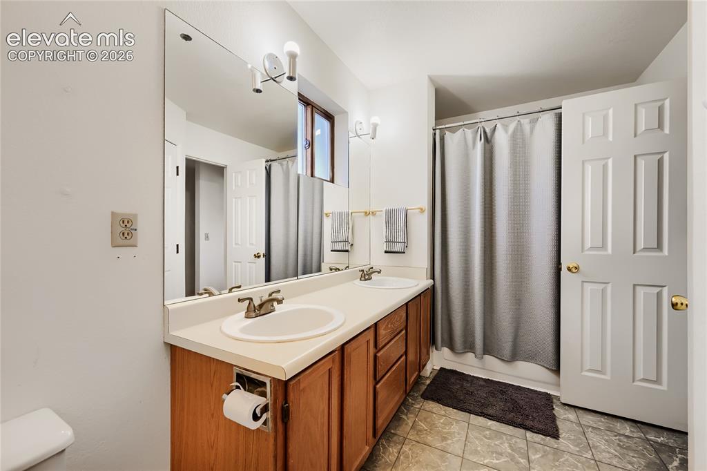 Image 21 of 37: Spa-inspired bathroom featuring a wood-finish vanity with dual-sink configu