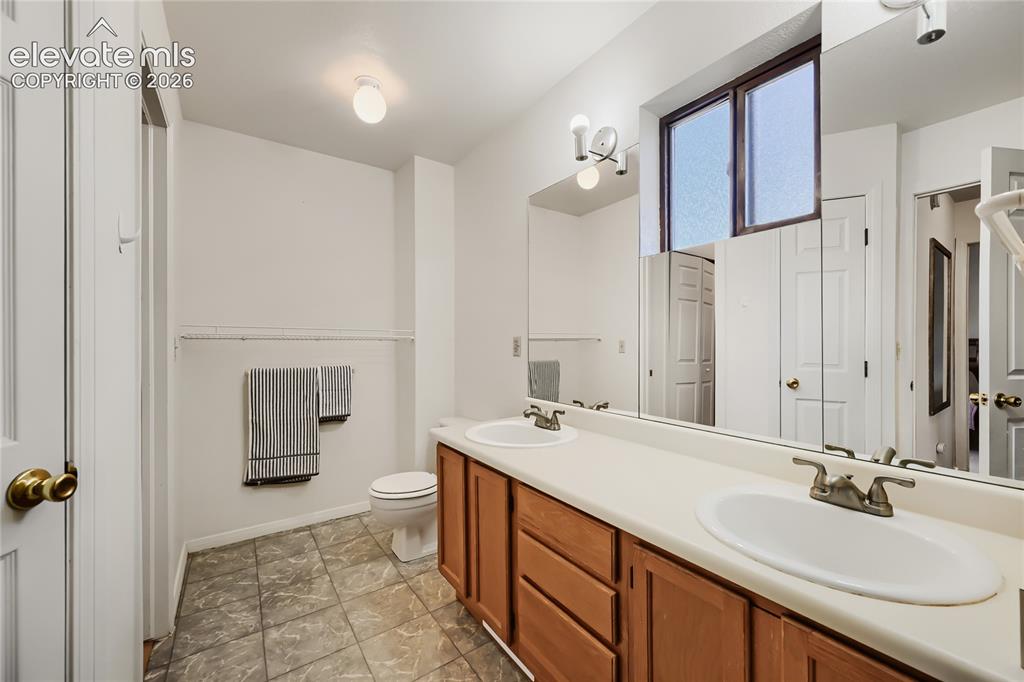 Image 22 of 37: Double vanity with integrated sinks, wood-finish cabinetry, a large mirrore
