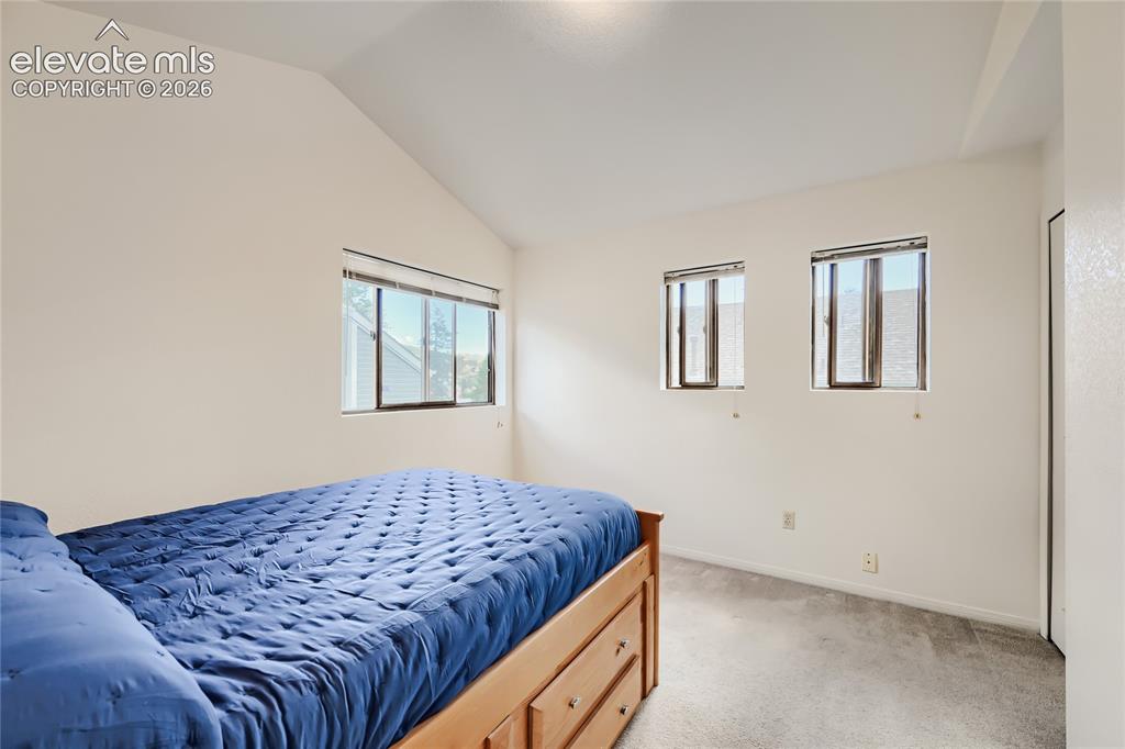 Image 23 of 37: Bright secondary bedroom with multiple windows providing natural light, car