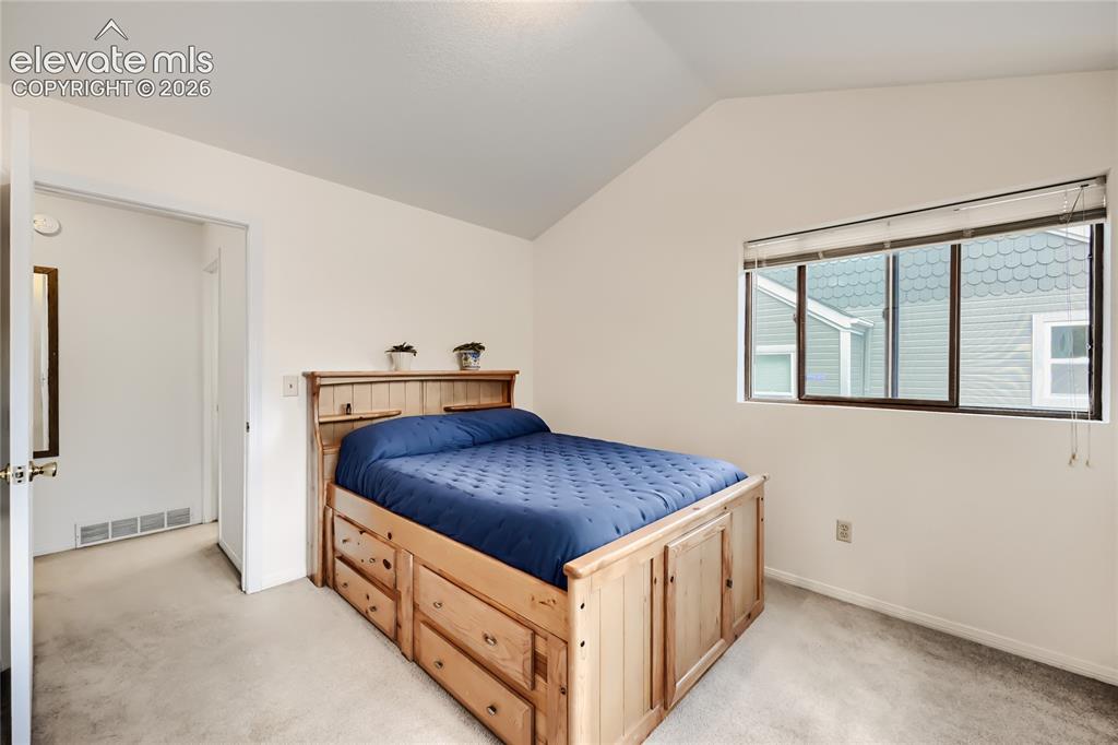Image 24 of 37: Vaulted ceiling, wall-to-wall carpeting, and a window with blinds