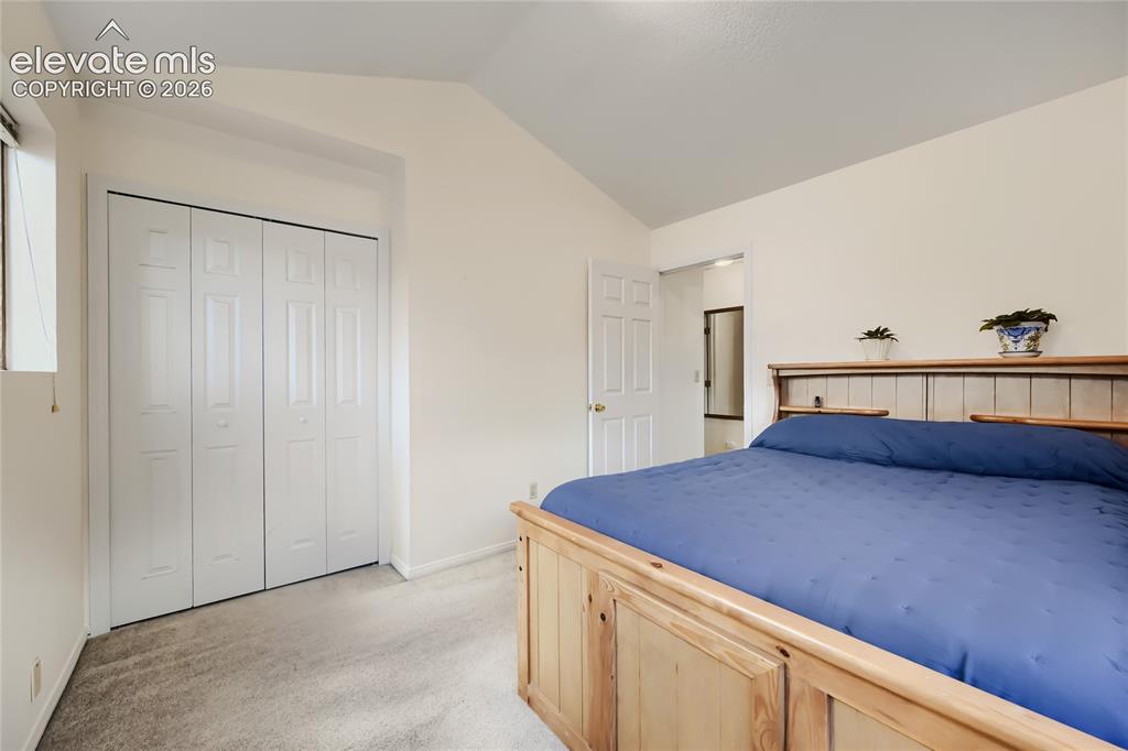 Image 25 of 37: Vaulted ceiling, bi-fold closet doors, wall-to-wall carpeting, and wood-fin