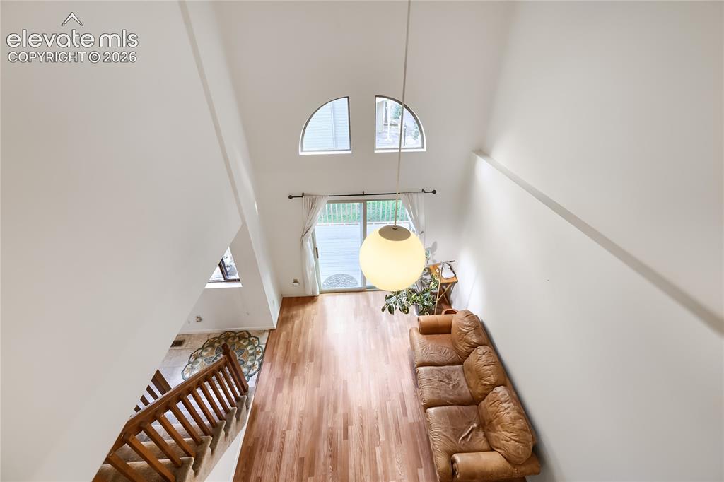 Image 7 of 37: High ceilings with an exposed beam and arch-top window, wood-finish floorin