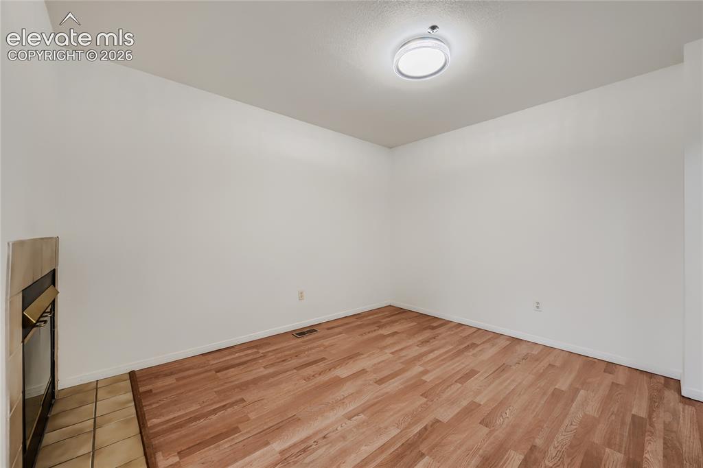 Image 9 of 37: Bright, open room with warm wood-finish flooring throughout, white walls, a
