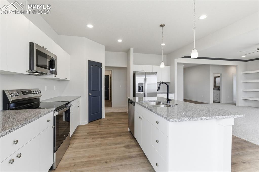 Image 11 of 30: Kitchen featuring appliances with stainless steel finishes, white cabinets,