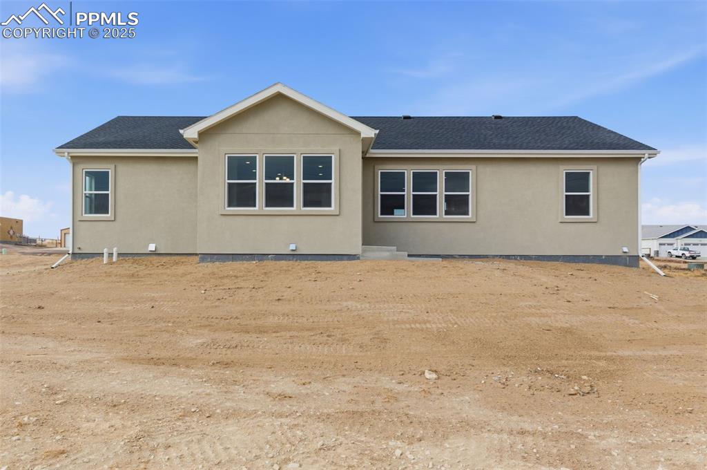 Image 29 of 30: Rear view of house with stucco siding and a shingled roof
