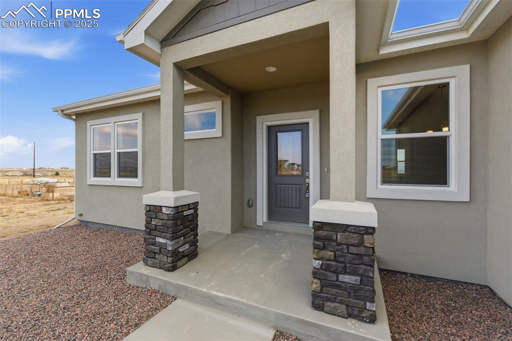 Image 3 of 30: Property entrance with stone siding and stucco siding
