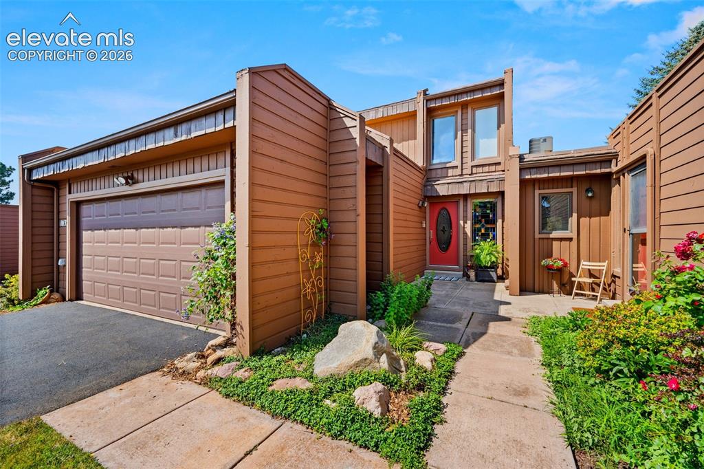 Image 1 of 48: Multi-level exterior with brown siding, a red front door, an integrated gar