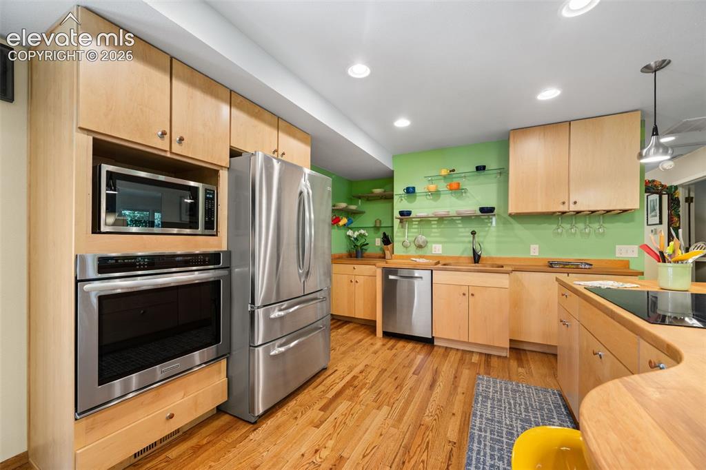 Image 12 of 48: Kitchen featuring natural wood cabinetry, wood-finish flooring, stainless s