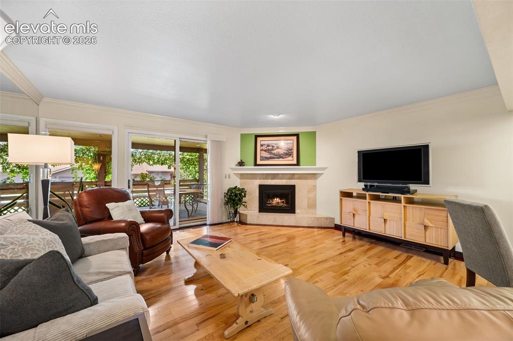 Image 15 of 48: Living area featuring wood-finish flooring, a corner fireplace with a stone