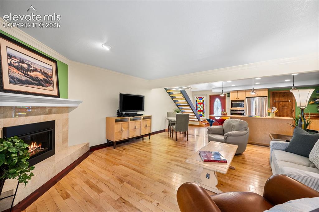 Image 17 of 48: Open-concept living area with light wood-finish flooring, a stone-clad fire