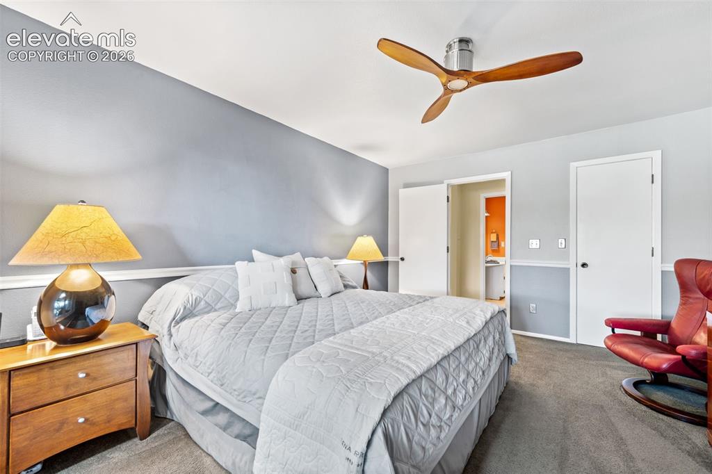 Image 22 of 48: Bedroom featuring a modern ceiling fan with wood-finish blades, soft gray w