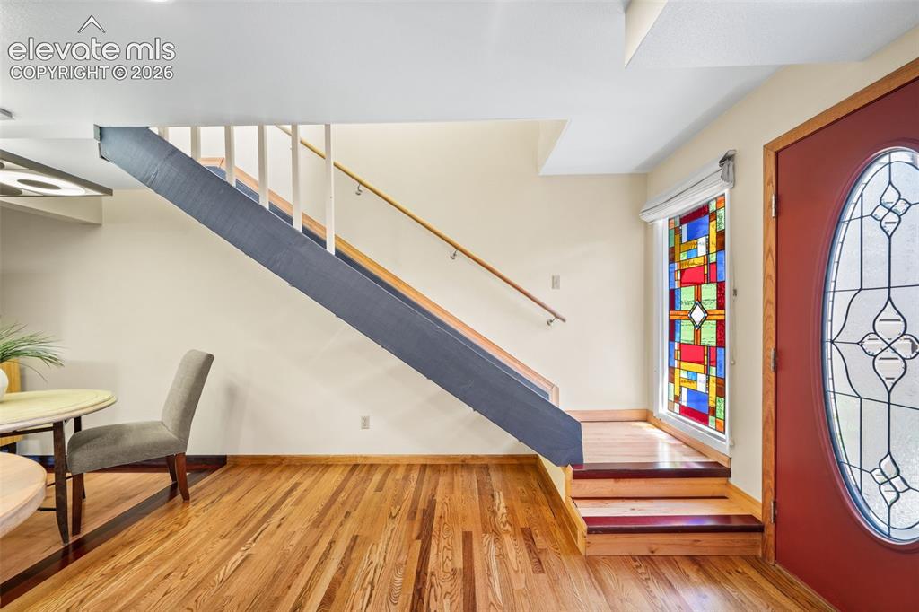 Image 23 of 48: Hardwood flooring throughout the entry, featuring a colorful stained-glass
