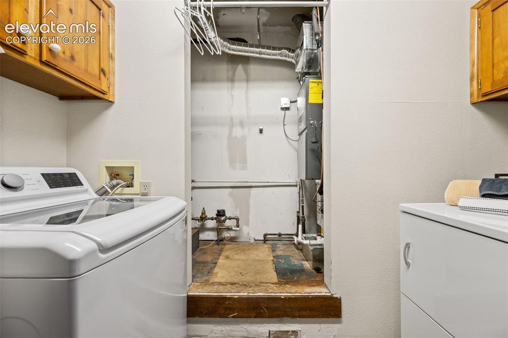 Image 32 of 48: Dedicated utility space featuring a washing machine, built-in wooden cabine