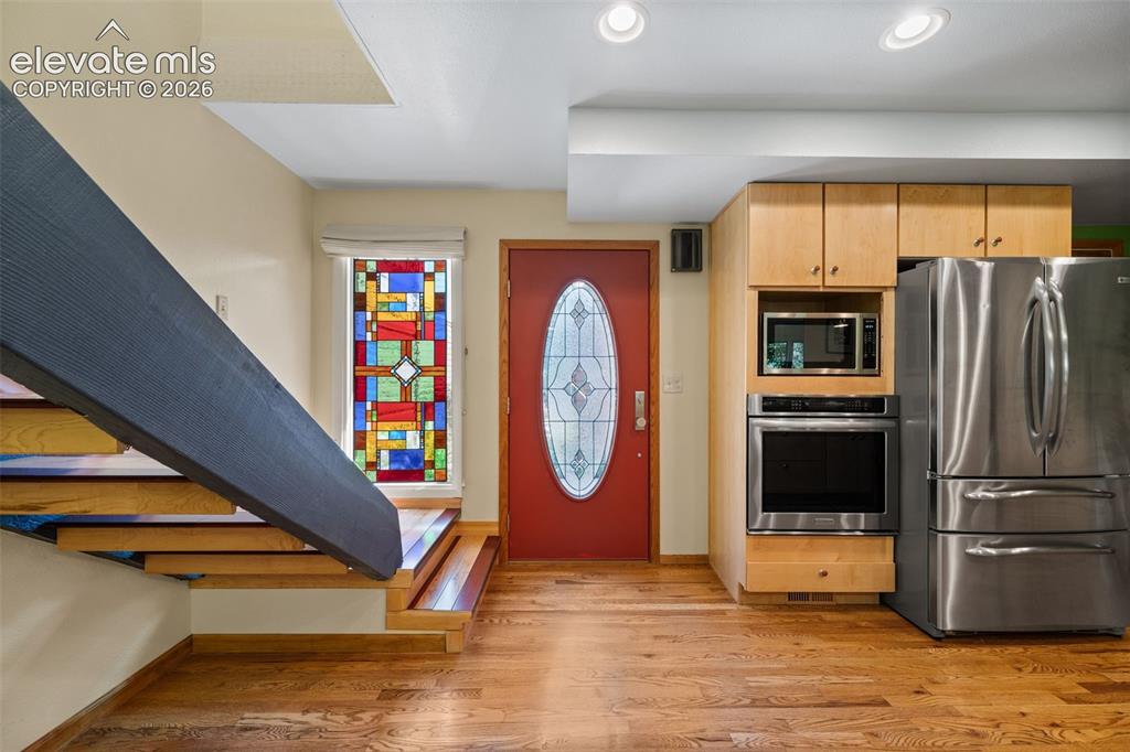 Image 5 of 48: Open-concept entry area featuring hardwood flooring, a red front door with