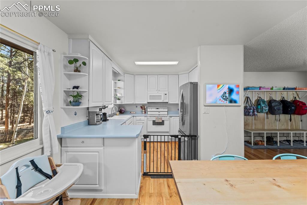 Image 10 of 47: Bright kitchen featuring white cabinetry and light blue countertops