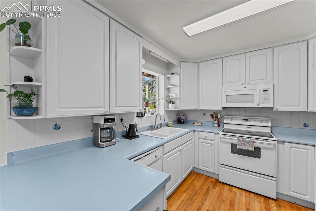 Image 11 of 47: Kitchen featuring white cabinetry, light blue countertops, a white built-in