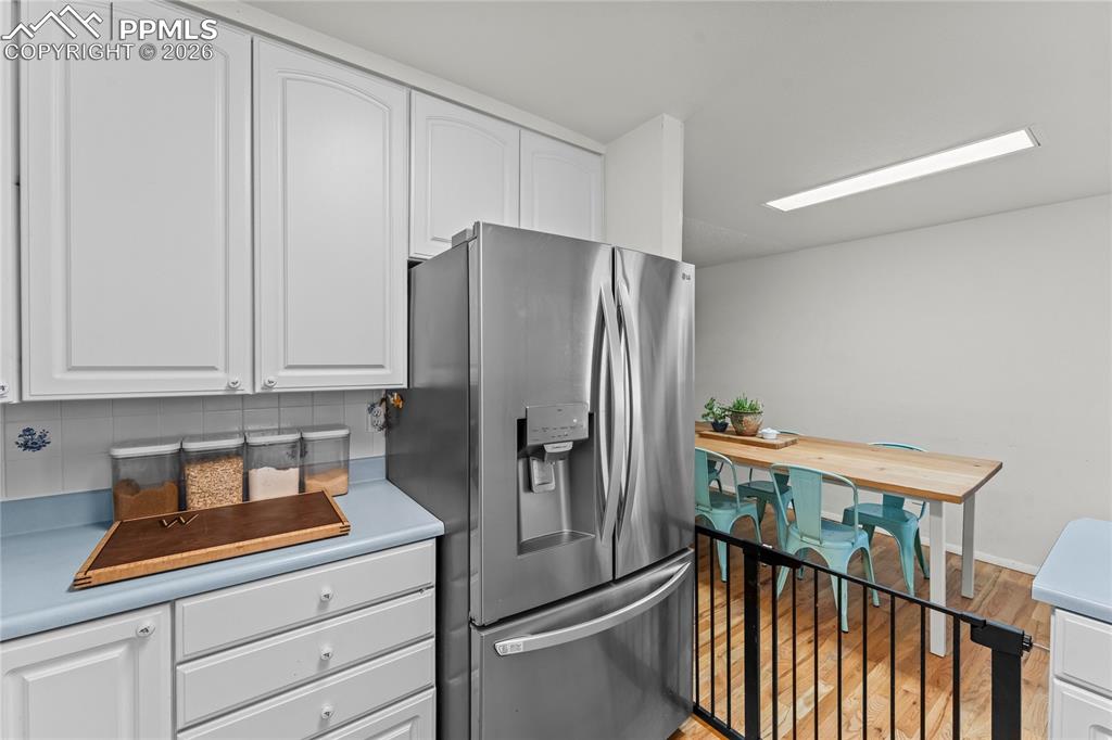 Image 12 of 47: Kitchen area featuring white cabinetry, light blue countertops, and white t