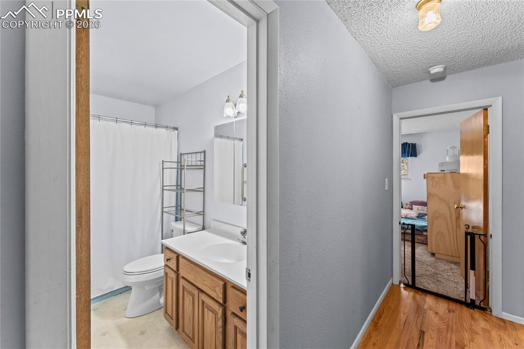 Image 15 of 47: Bathroom featuring a single vanity with a white countertop and natural wood