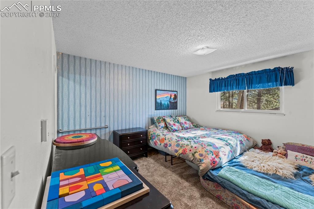 Image 18 of 47: Bedroom featuring light blue striped wallpaper, a window with exterior tree