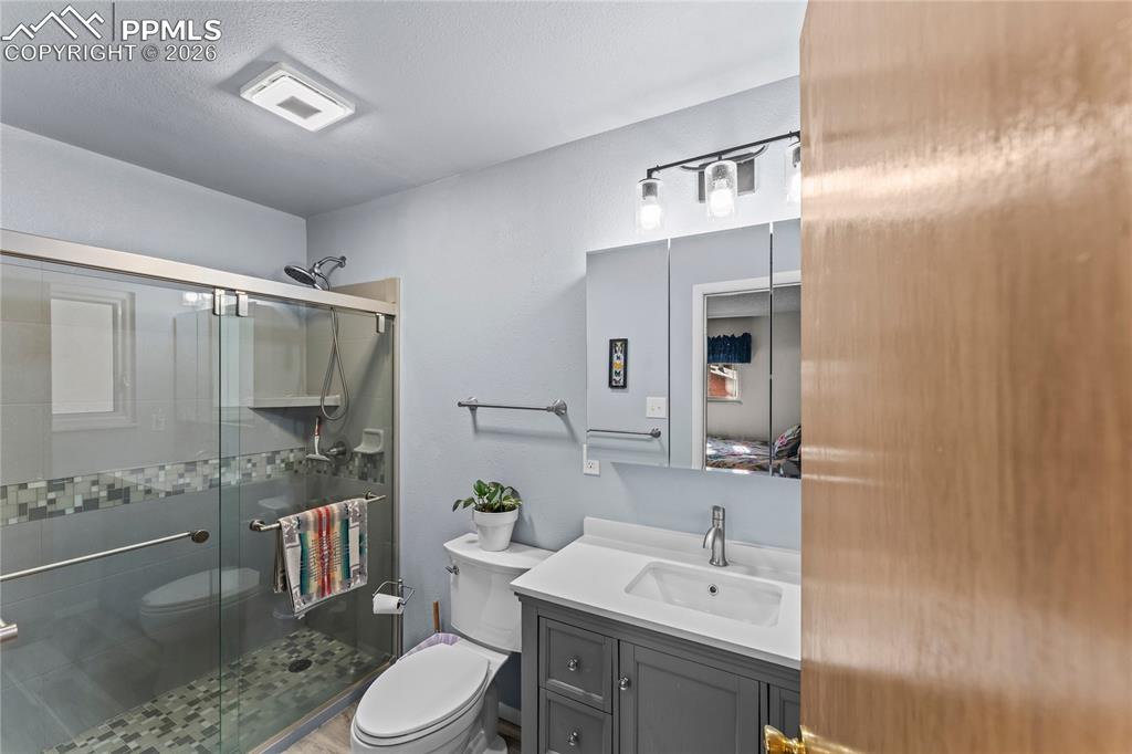 Image 24 of 47: Bathroom featuring a glass-enclosed shower with mosaic tile accents, a gray