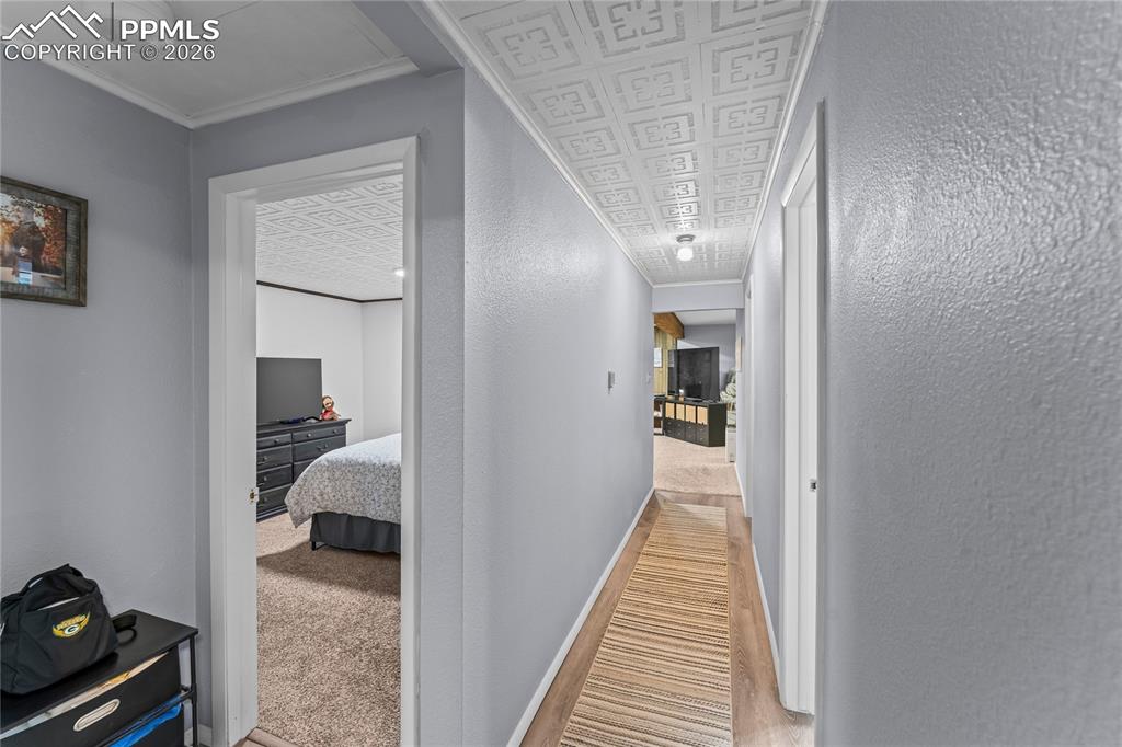 Image 28 of 47: Basement hallway with light gray walls and patterned ceiling, featuring woo
