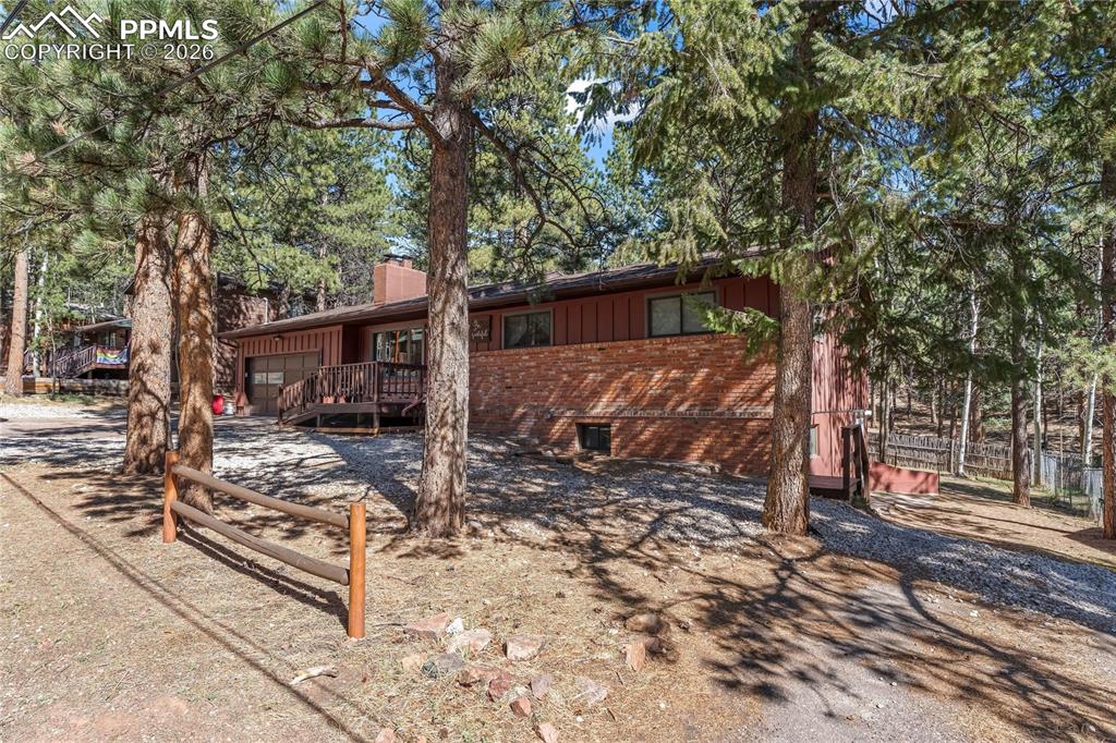 Image 3 of 47: Wood-sided residence featuring a brick facade, attached garage, and a woode