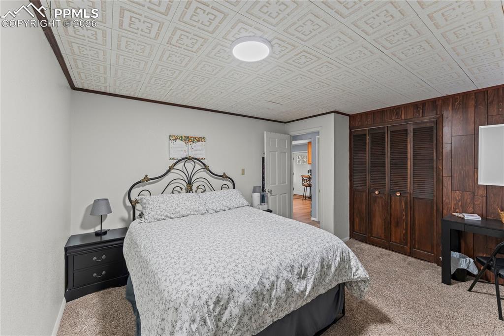 Image 34 of 47: Room featuring patterned ceiling, wood-paneled wall, bi-fold closet doors, 