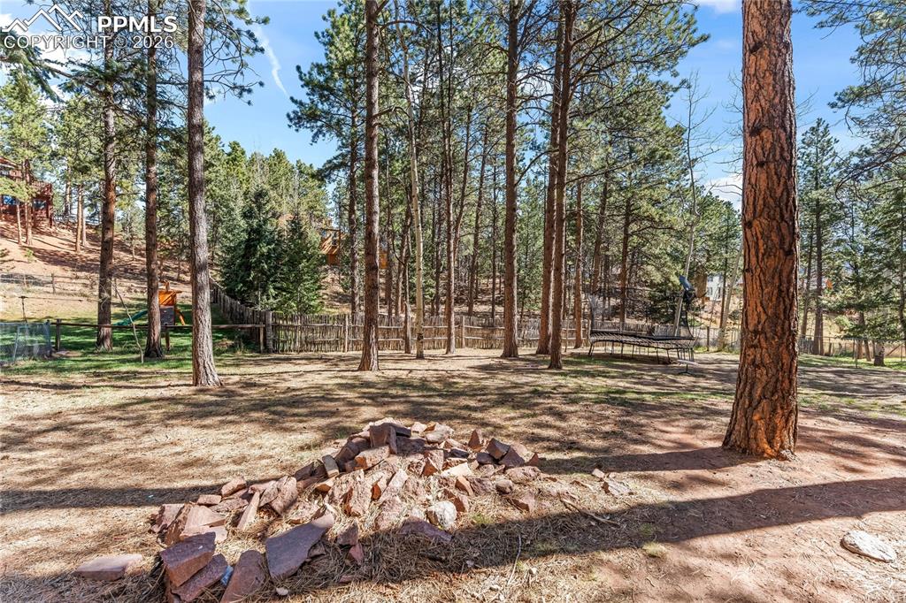 Image 41 of 47: Wooded property featuring mature trees and a rustic stone fire pit