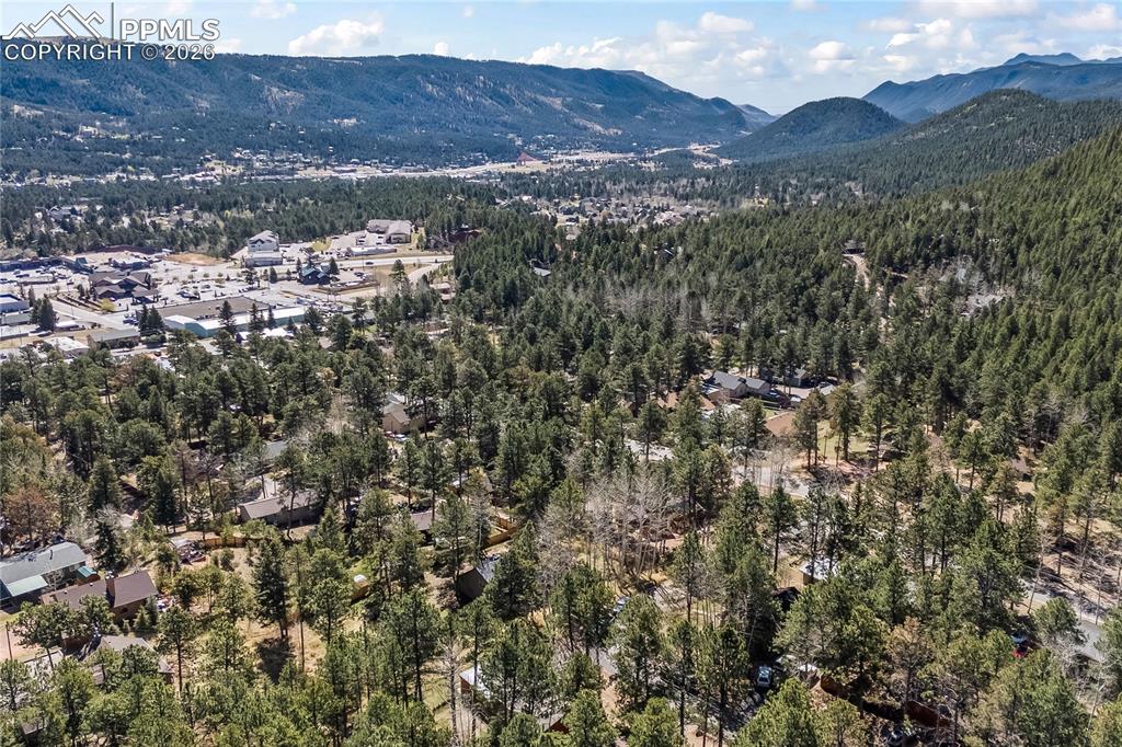 Image 46 of 47: Expansive mountain landscape featuring dense evergreen forests and a scatte