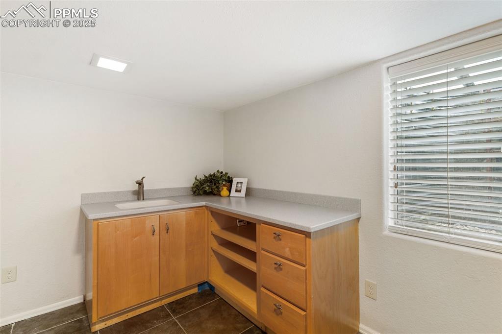 Image 29 of 35: Kitchen with dark tile patterned flooring and light countertops