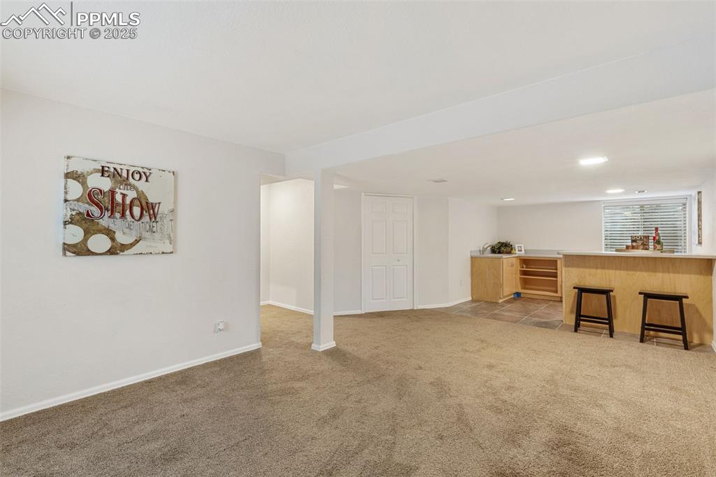 Image 30 of 35: Living area featuring wet bar and light colored carpet