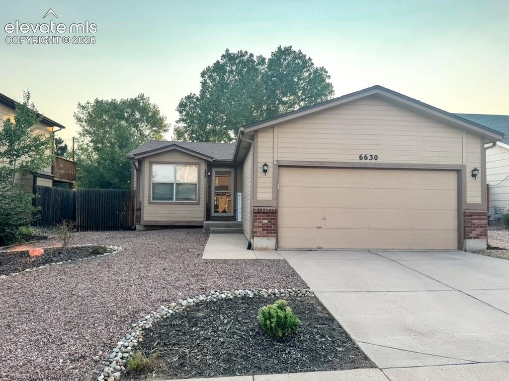 Caption: Single-story exterior with siding and brick accents, a two-car garage, and a concrete driveway